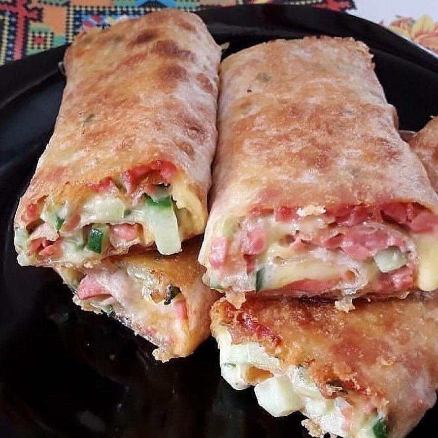 Горячий рулет из лаваша. 
 
Ингредиенты: 
-Лаваш 2 шт 
-Сыр плавленный 300 г 
-Колбаса копченая 200 г 
-Огурец соленый 3 шт 
-Вареное яйцо 3 шт 
-Зелень любая по вкусу 
-Майонез по вкусу 
-Чеснок 3 зубчика 
-Сливочное масло 50 г 
 
Приготовление: 
Сыр размягчить, яйца, огурцы и зелень мелко нарезать и добавить к сыру, все хорошо перемешать. Добавьте майонез и чеснок выдавленный через чеснокодавилку 
Лаваш выложите на доску, смажьте майонезом, выложите тонкие ломти колбасы, поверх состав из плавленого сыра и других компонентов, затем сверните лаваш в рулет. Таким же образом подготовьте и второй лаваш 
Запекать лаваши в разогретой духовке на противене, при температуре 180 градусов 15 мин