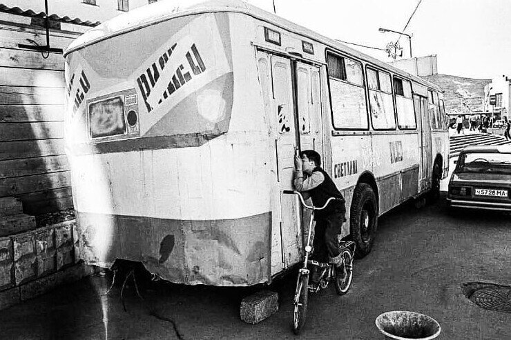 Мальчик подсматривает за показом фильма в видеосалоне, который находится в автобусе, Магадан, 1994 год.