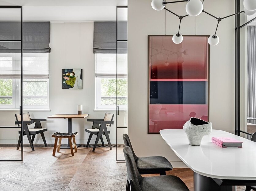 При кухне изначально был балкон-лоджия, проём которого расширили, чтобы пространство выглядело единым, но при необходимости отделялось лёгкими раздвижными перегородками. Между окон стоит небольшой стол, который современем стали называть «шахматным», потому что именно тут проходят занятиясына по шахматам и семейные шахматные турниры. Композицию дополнила парастульев Cassina. Над столом картина художницы Марии Костаревой. Украшением обеденной зоны стала картина авторства художника Владимира Глынина. На столе — керамическая ваза, Forest is Calling.