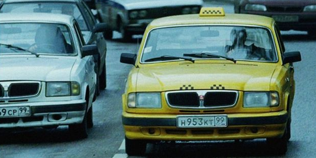 Яркое такси в сером городском потоке