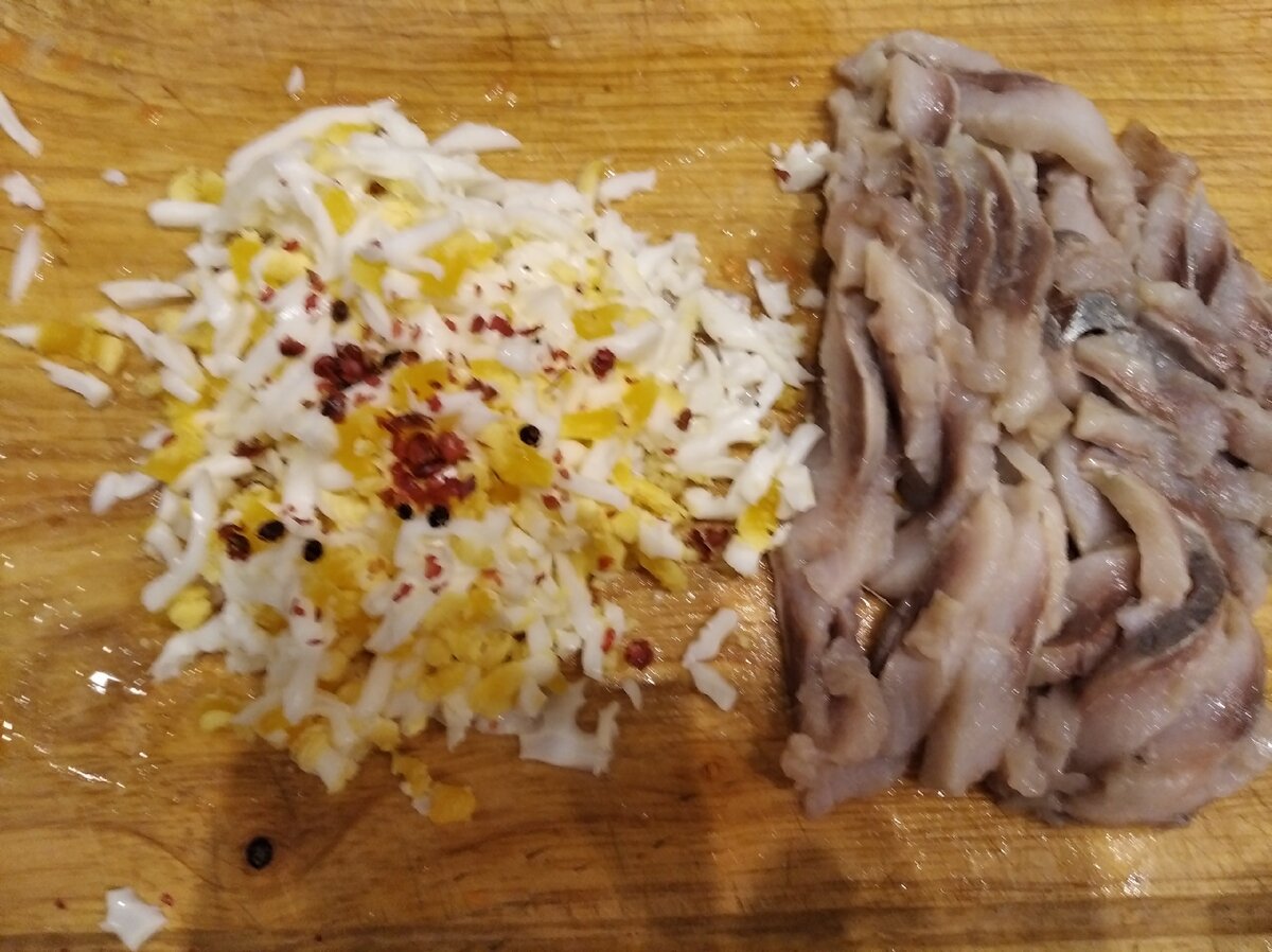 Нарежем тонкими ломтиками. Яйца - на крупной терке. Присыплем розовым перцем.