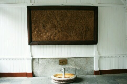 На панно изображена легенда об основании города - Карл IV гнался за оленем, который перепрыгнул источник, а королевская псина попала в горячую воду и подняла вой. На шум съехались все охотники и вытащили собаченцию. На удивление всем псина быстро вылечилась, а врачи Карла IV отметили лечебные свойства источника. Так король Германии обратил внимание на это место, а позже заложил город Карлсбад. 