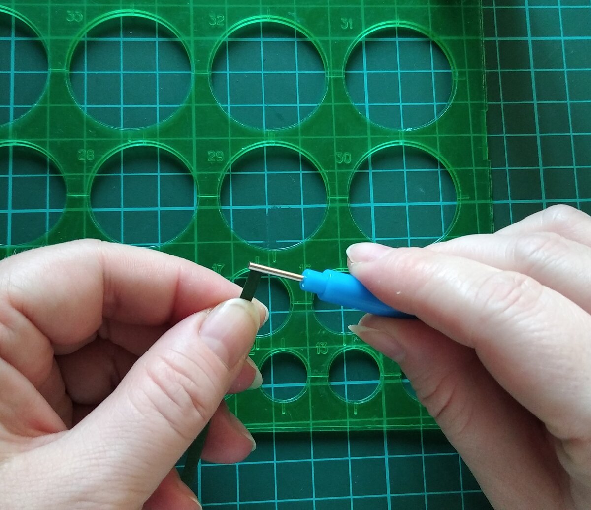 вставляем полоску темно-зеленой бумаги в инструмент для квиллинга