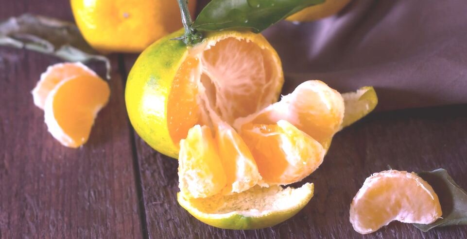 Мандарины с зеленоватой корочкой снаружи, спелые внутри.