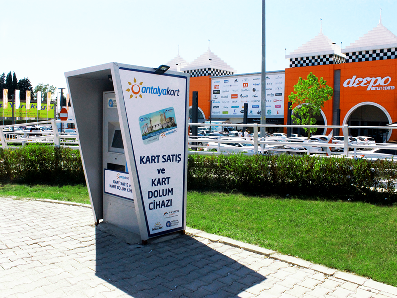 Терминал для покупки транспортной карты Antalyakart (Антальякарт). Но тоже лучше воспользоваться сторонней помощью или дождаться помощи водителя автобуса.
 Внимание! Приобрести  карту можно только за местную валюту лиры.
 Рубли или доллары или евро можно обменять в аэропорту, но только не большую сумму, так как курс "не вкусный".