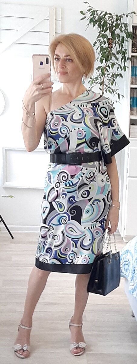 Платье с одним рукавом , подпоясанное широким ремнём.