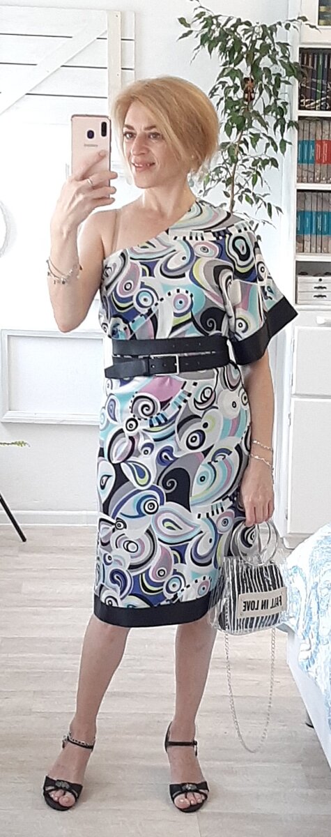 Платье с одним рукавом, подпоясанное ремнём.