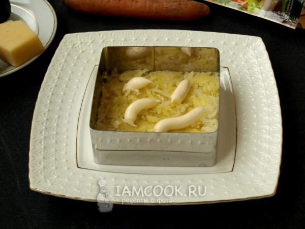 2. Формировать салат будем с помощью специальной формочки. У меня квадратная форма, ставим её по центру тарелки и выкладываем на дно тёртый картофель, смазываем слой майонезом.