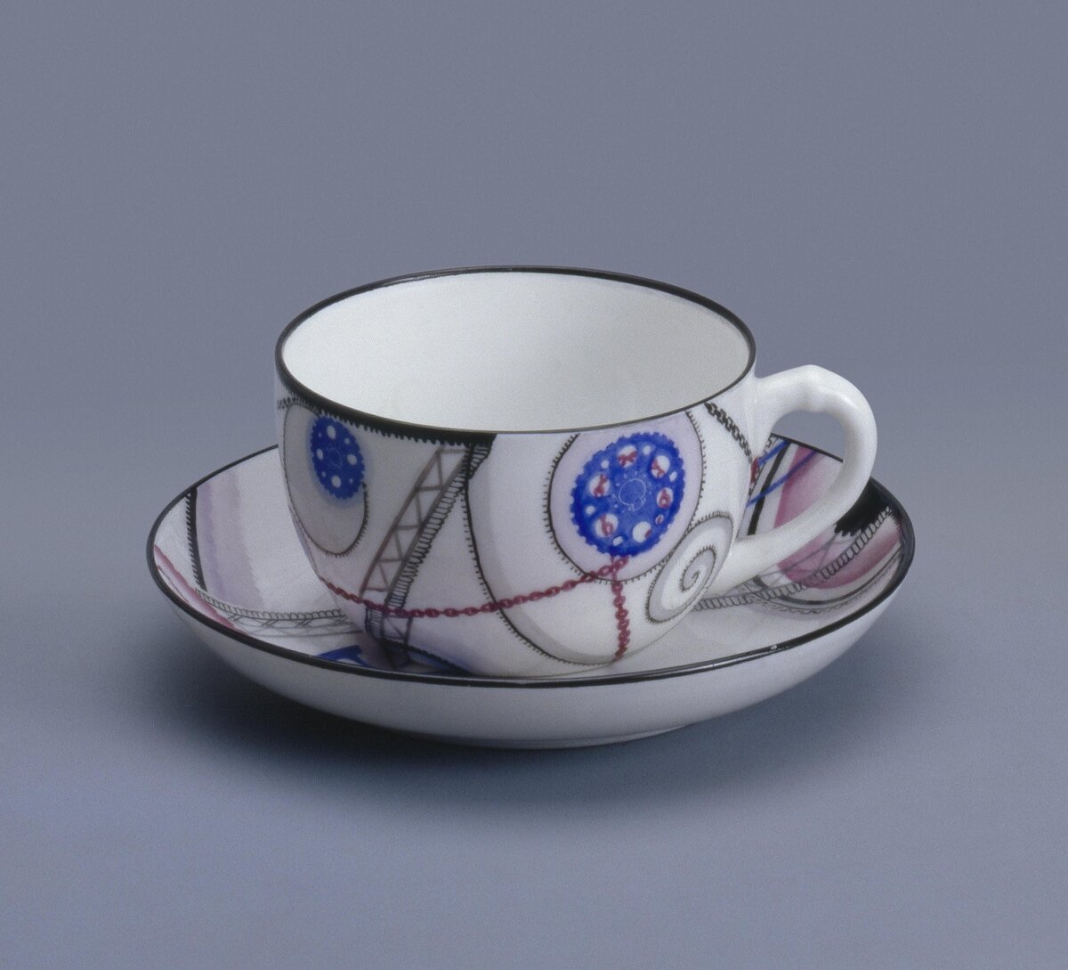 Чашка с блюдцем из комплекта "Сервиза №5" ("Индустриальный"), 1931. Автор рисунка и исполнитель росписи - Протопопова Л.В. Роспись надглазурная полихромная. Размеры: 5,5*11,4*9,1 см. (чашка) и 2,4*14,5 см. (блюдце). Предмет поступил в Эрмитаж в 2002. Передан в составе Музея Фарфорового завода. Инв. номер Мз-С-2453. Изображение взято из каталога Эрмитажа.