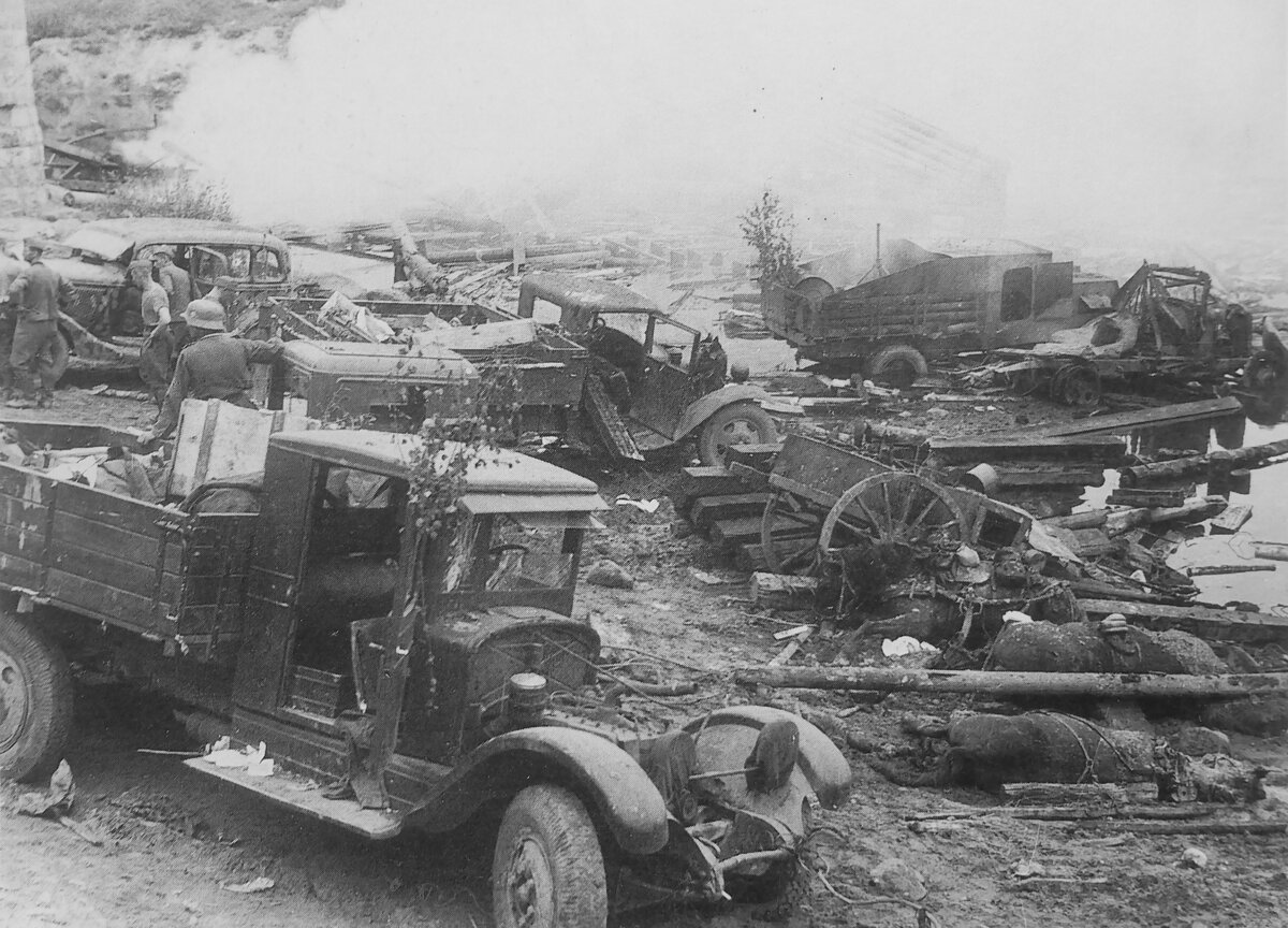 Брошенные возле переправы грузовики, автомобили и другая армейская техника. 