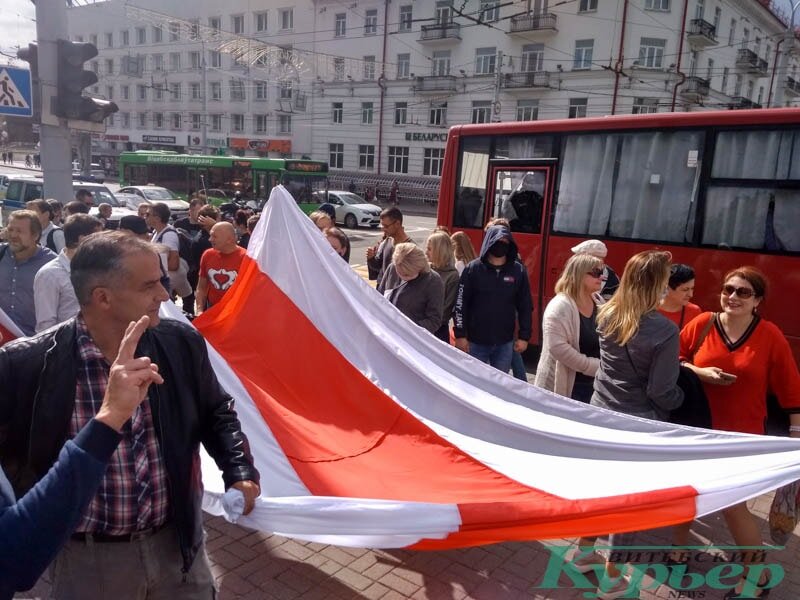 Колонна  около 14.20 на перекресстке Фрунзе и Ленина. На заднем плане виден  автобус с милиционерами, из окна на демонстрантов смотрит сотрудник.  Фото Анастасии Вереск