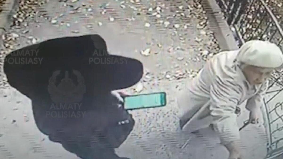    Женщина в черной одежде стоит возле бабушки у подъезда:YouTube/Almaty Polisiasy