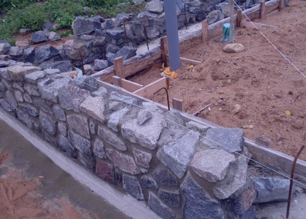 Забор из камня с фундаментом, столбами и кованными элементами