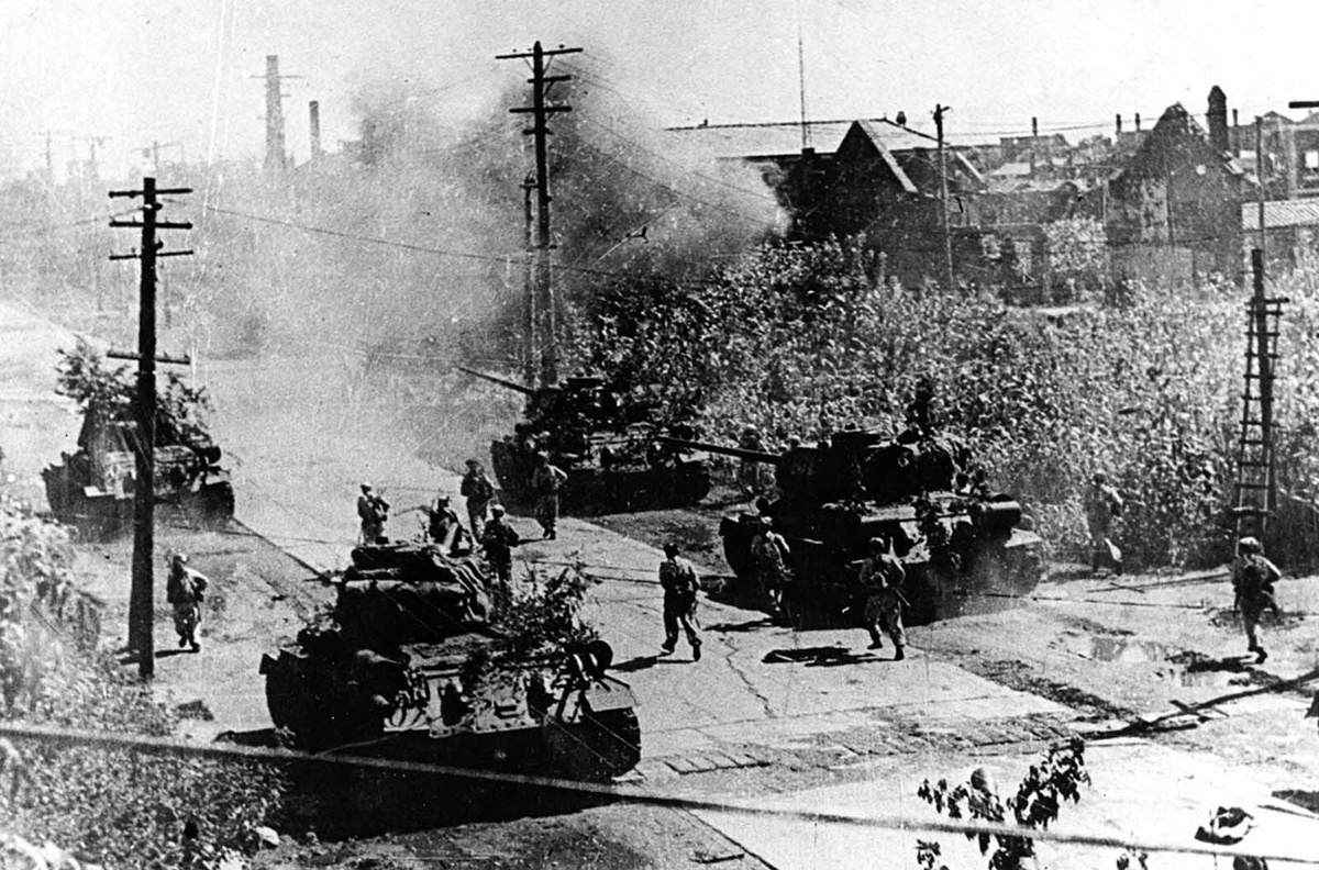 Утомленная войной кореянка с братом на спине пробирается мимо остановившегося танка М-26 в Хэнджу, Корея.  9 июня 1951 г.-2
