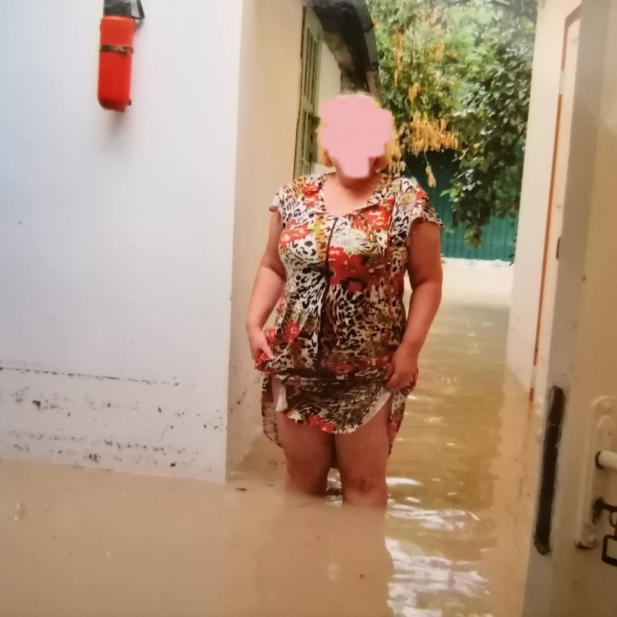 Хозяка квартиры, с тоской оглядывающая ущерб. На белой стене сарая хорошо видно, докуда дошла вода. Личное фото