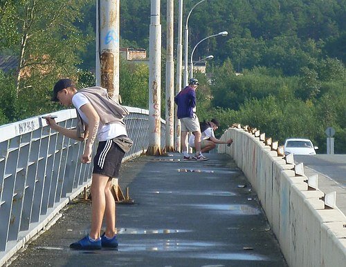 Двое подростков тегают . Один маркером, а другой же аэрозольной краской из баллончика.