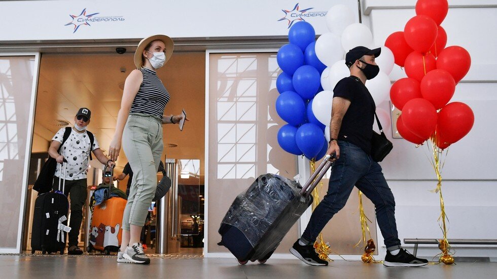 Туристы в масках для лица изображены в Международном аэропорту Симферополя, Крым, Россия. © Спутник / Константин Михальчевский
