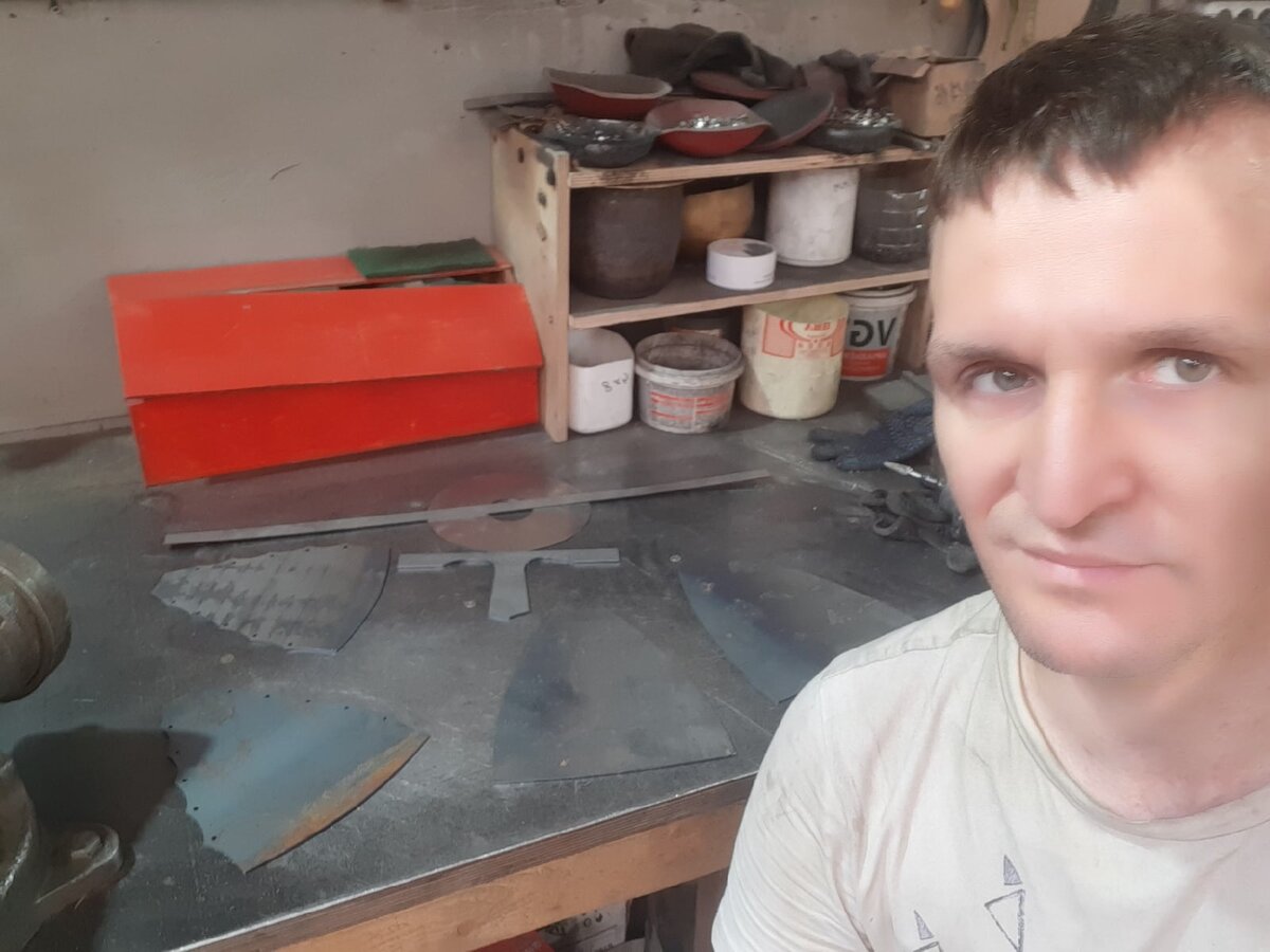 Мастер Александр Панаскин. За его спиной на верстаке - четыре куска железа - заготовка под будущий шлем. А также основа наносника