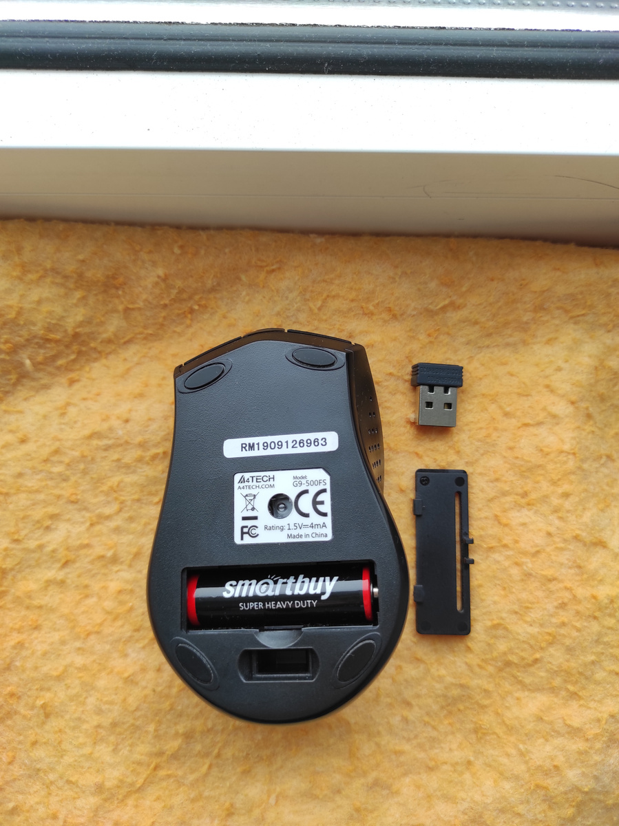 Задняя часть компьютерной мыши A4Tech G9-500FS с открытой крышкой батарейного отсека. По карусели фото 2 - можно увидеть место для большого пальца правой руки, благодаря такому узору палец не скользит