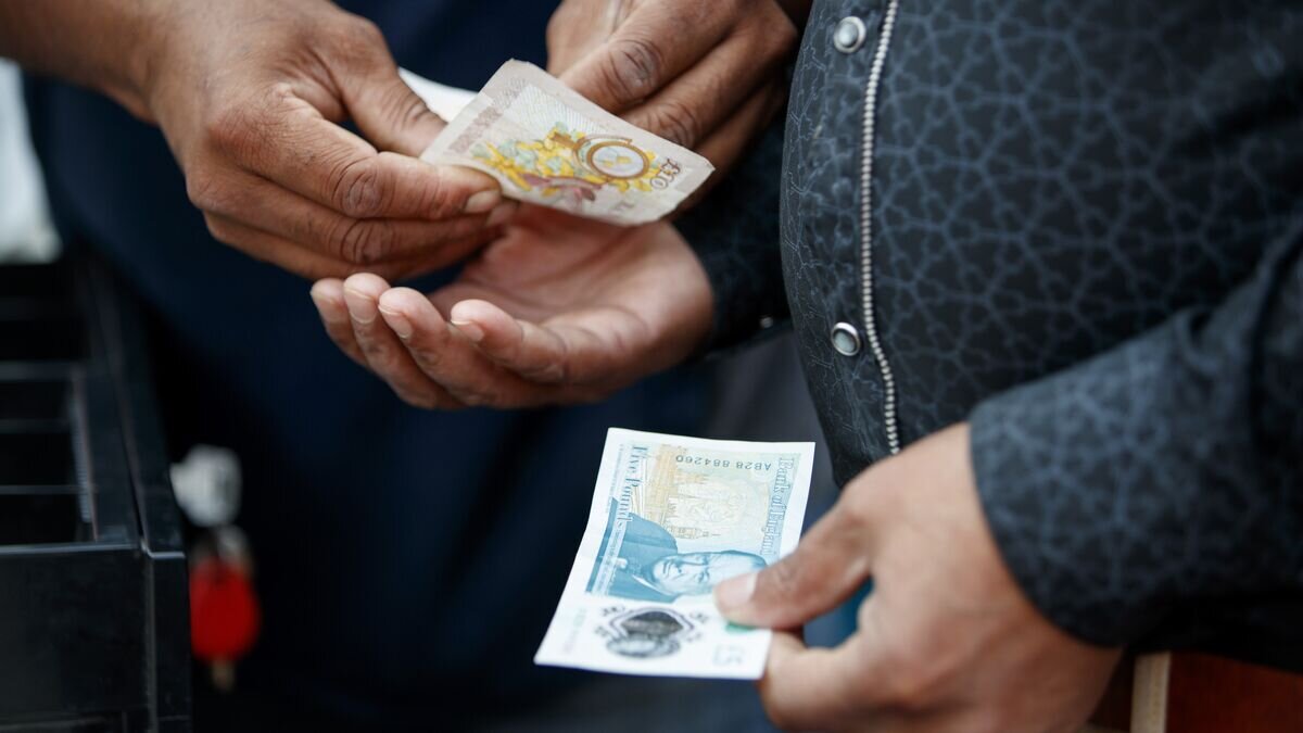 Покупатель продавец обмениваются купюрами в 5 и 10 фунтов стерлингов© AFP 2022 / Tolga Akmen