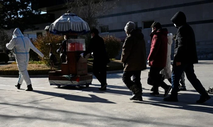 Члены семьи следуют за урной с прахом близкого человека в крематории в Пекине 22 декабря 2022 года. (STF/AFP via Getty Images)