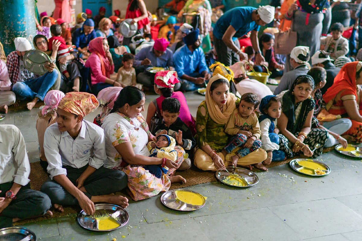 Индийцы едят карри в бесплатной столовой Гурдвары Бангла Сахиб