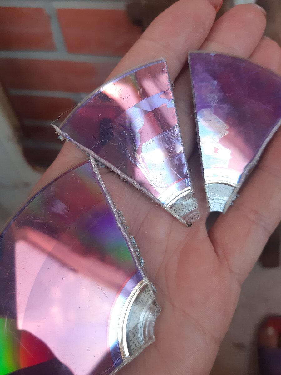 Берем CD диск, режем пополам, половинку еще на 4 части. На этом фото хорошо видно разницу между резкой паяльником и ножницами- в том месте где я разрезала ножницами появилось множество сколов и трещин.