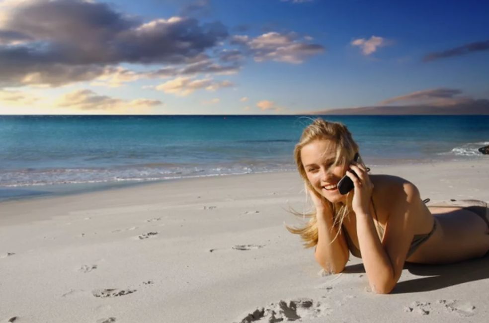 Девушка говорит по телефону на пляже. Девушка на пляже с телефоном. Связь на отдыхе. Девушка роуминге.