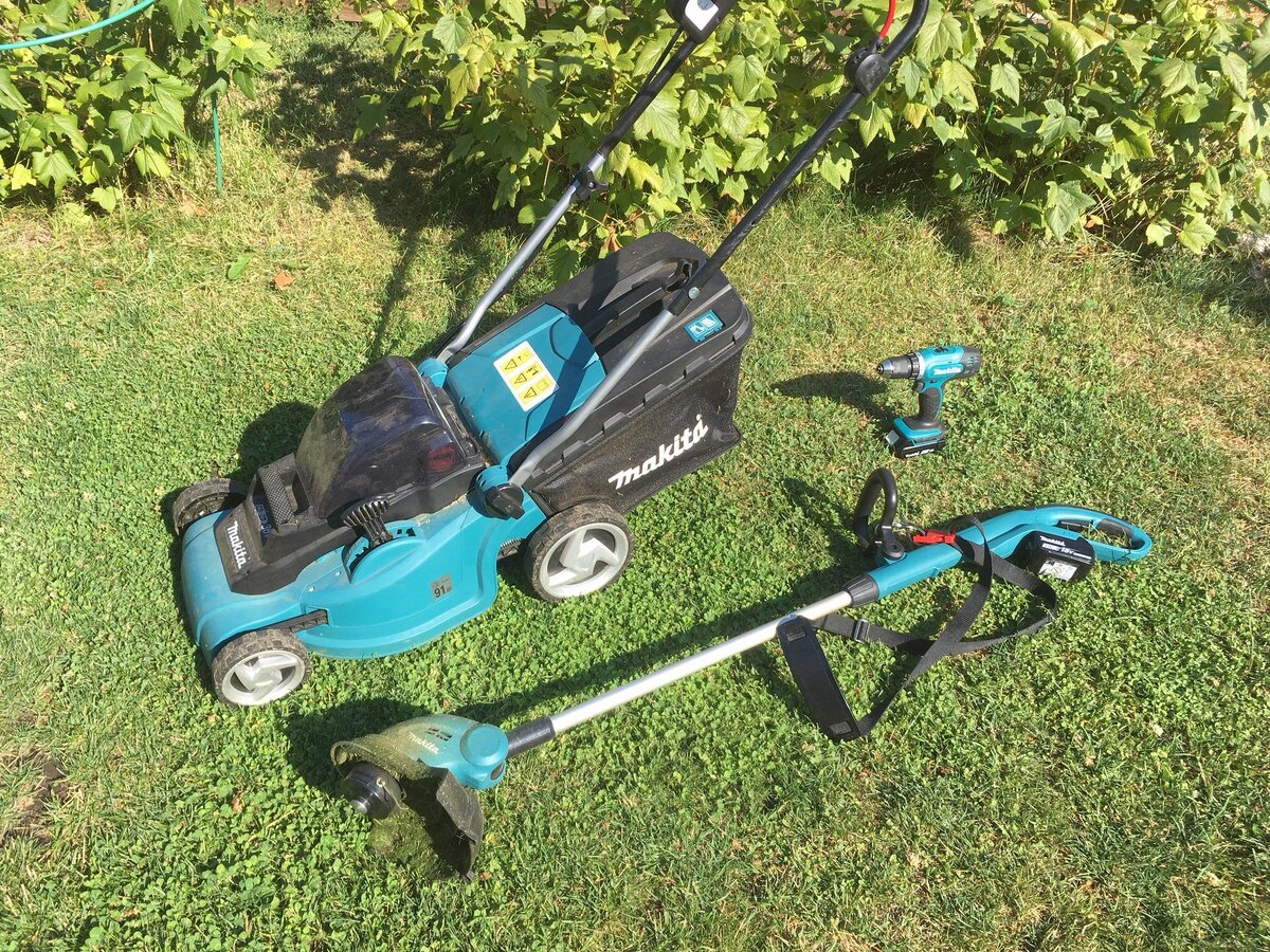 Две косилки и шуруповерт в единой цветовой гамме на фоне травы.