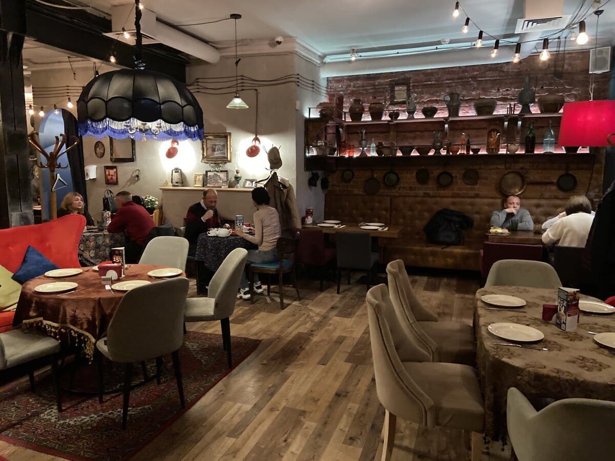 Столы со скатертями и без. Скатерти с бахромой или скатерти с узорами, напоминающими ковры советского времени. Винная и кухонная утварь на полках. 
Фото автора (листай)