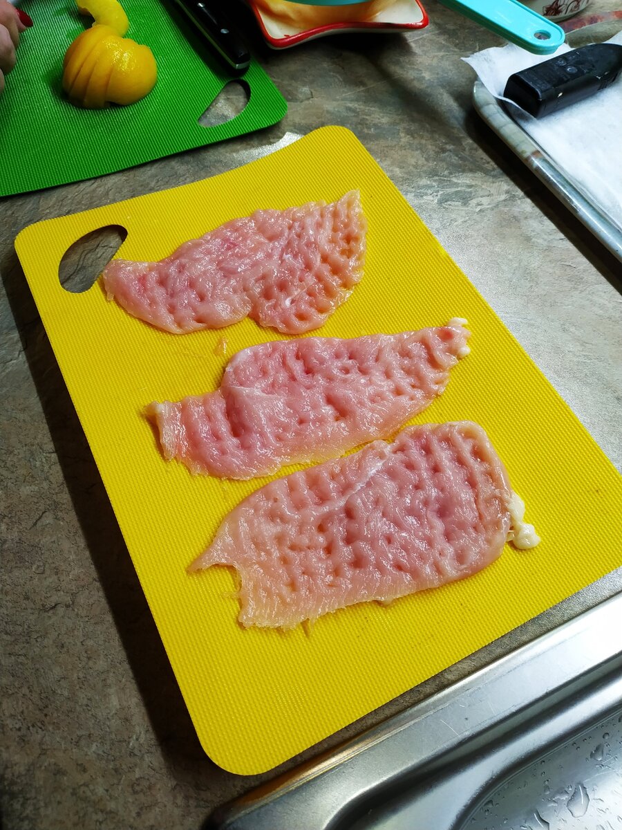 Нарезаем тонкими пластами филе куриной грудки и отбиваем.