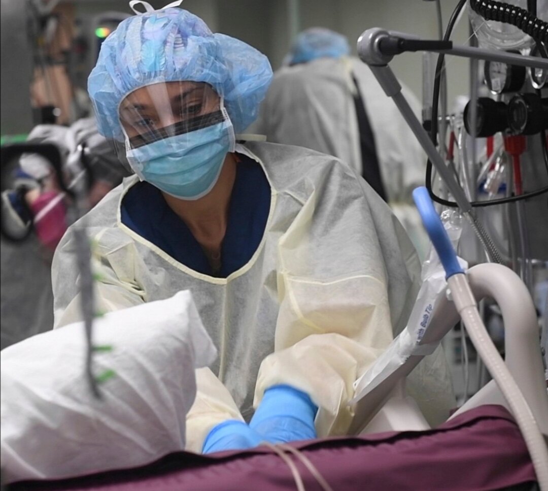 Медсестра готовит больного COVID-19 пациента к процедуре в отделении реаниматологии на борту американского корабля-госпиталя.