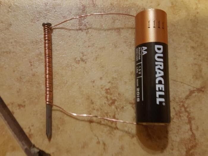 Уронили что-то металлическое на ковер с длинным ворсом? В такой ситуации помог бы магнит, однако он не всегда есть в доме. Благо, сделать электромагнит своими руками совсем не сложно. Во-первых, нужно раздобыть медную проволоку, батарейку и какой-нибудь крепежный элемент (болт или гайку). Во-вторых, нужно все это соединить: проволока наматывается на болт в одном направлении, а ее концы подсоединяются к полюсам элемента питания. Магнит готов.