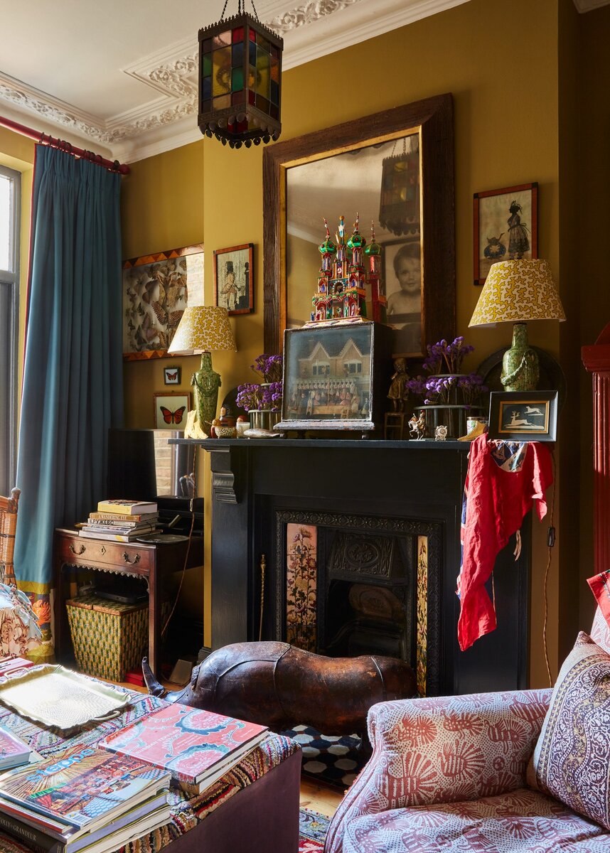 Фото: Боз ГаговскийКамин в столовой оригинальный, эпохи “Искусств и ремесел”; кресло, Love Your Home, в ткани, Volga Linen; фонарь антиквар­ный; абажуры в ткани, Colefax and Fowler; на шторах ручная вышивка по мотивам иллюстраций Ивана Билибина к сказкам Пушкина.