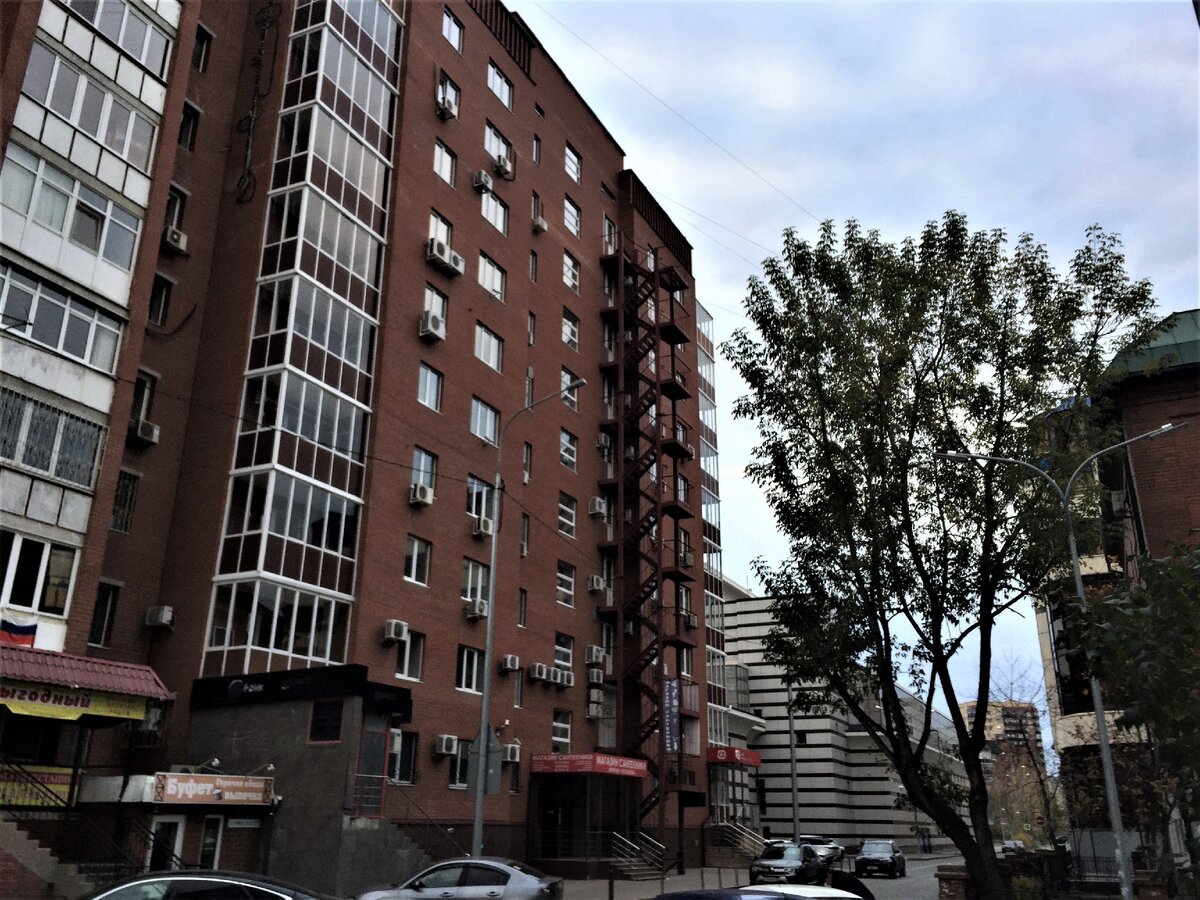 Здание музея выглядывает серым корпусом из-за кирпичной стены соседнего здания. 