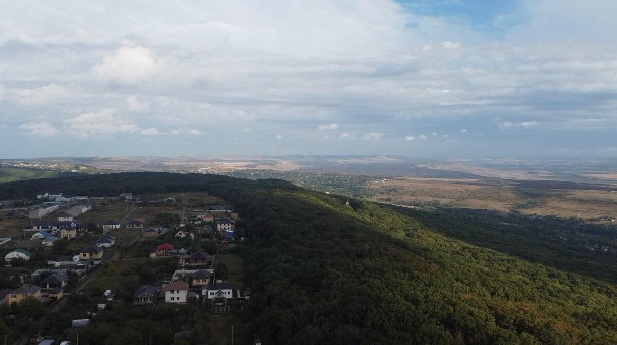 Так выглядит место, где расположен наш участок. Рядом с нами густая стена леса. В нем много родников, образующих небольшие водопады, пешеходные тропы, много грибов и кизила. А если присмотреться, то в лесу виднеется маковка колокольни мужского монастыря. Соседи говорят, что звона почти не слышно, так что мы не стали считать это минусом