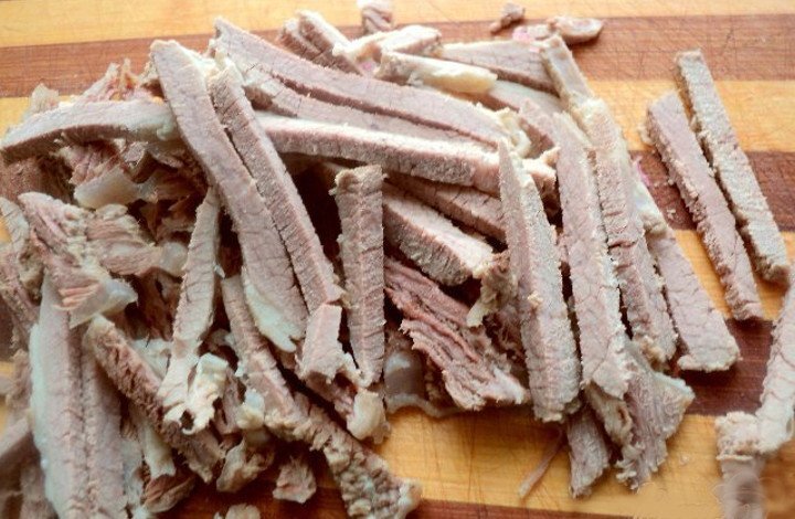 говядину замачиваю в соленой воде на 2 часа,затем отвариваю с приправами до полной готовности,остужаю и нарезаю брусочком.