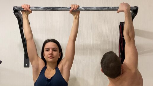 Девушка подтягивается с блином на турнике