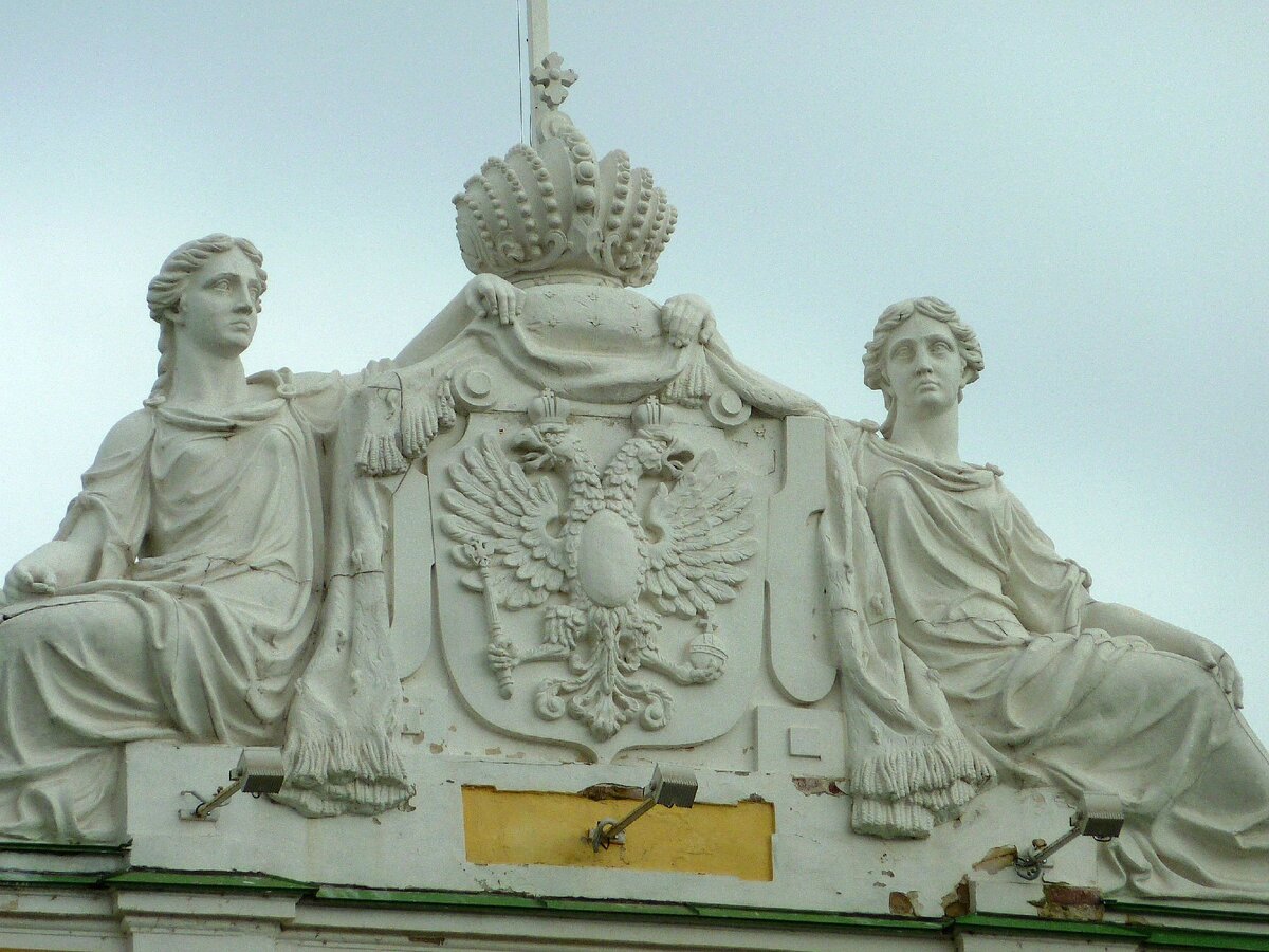 Аттик Путевого дворца в Твери, который украшают герб, императорская корона и аллегории "Волга" и "Россия" по бокам