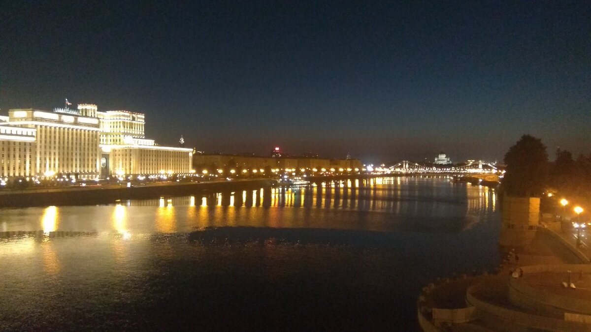 Вид с моста вниз по течению на центр Москвы. Красиво подсвеченное здание - Министерство обороны. Назад примерно 5 лет оно заметно выросло и вверх и в объеме. Виден Крымский мост и храм Христа Спасителя.
