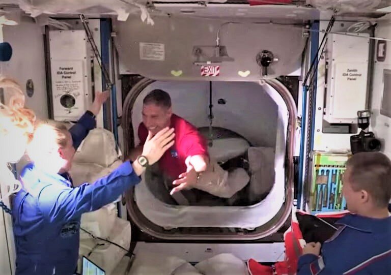 Командир Crew Dragon Майкл Хопкинс приветствует астронавта НАСА Кейт Рубинс, когда он садится на космическую станцию