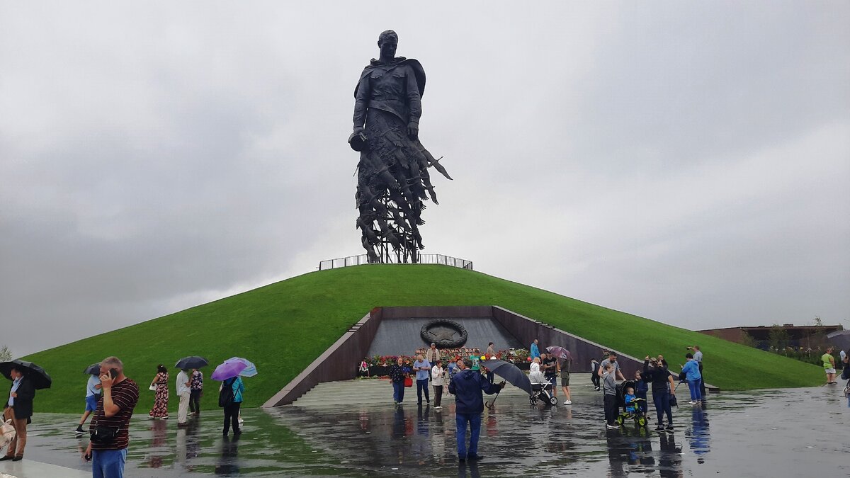 Несмотря на непогоду, у памятника много людей.