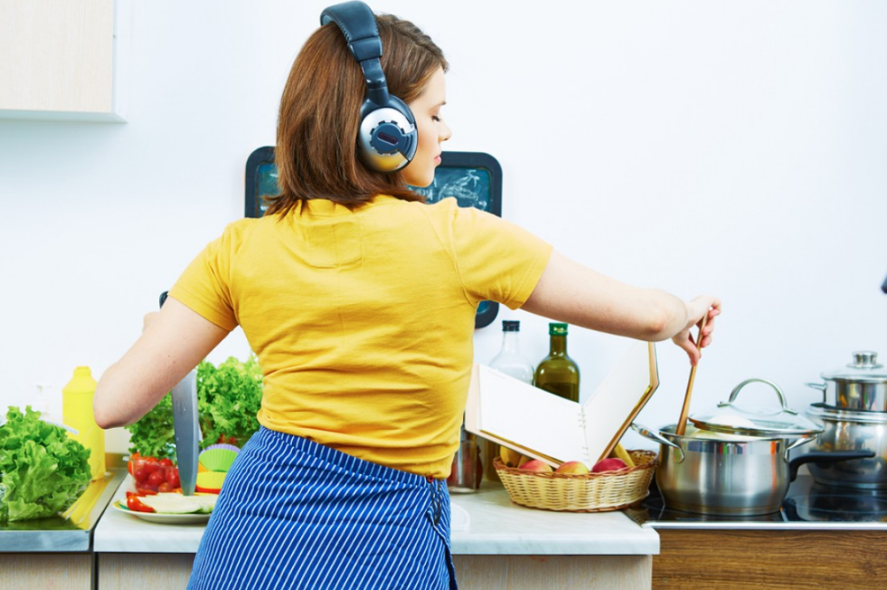 She cooks. Женщина готовит. Женщина в наушниках на кухне. Женщина готовит на кухне. Уборка и готовка.