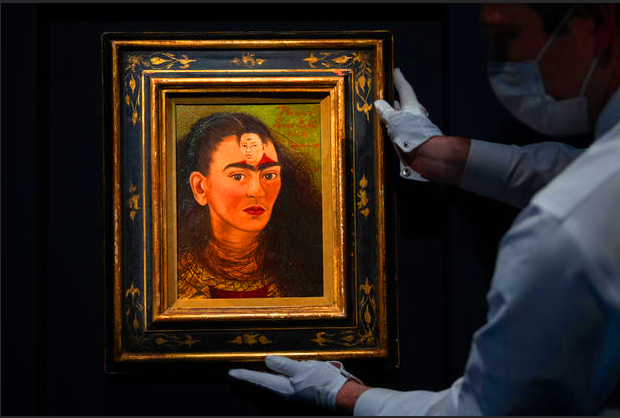 Художник держит последний автопортрет Фриды Кало «Диего у йо» во время пресс-показа коллекции Маклоуна