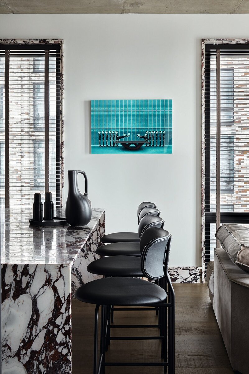 Фото: Сергей Ананьев; стилист: Наталья ОнуфрейчукФрагмент зоны кухни. Кухонный остров из мрамора сделан на заказ; барные стулья, Gubi; на стене работа “3 команды” Хардибади из галереи YellowKorner; аксессуары, GK Concept.