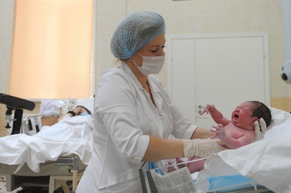     Медицинский работник осматривает новорожденного ребенка. Юлия ПЫХАЛОВА