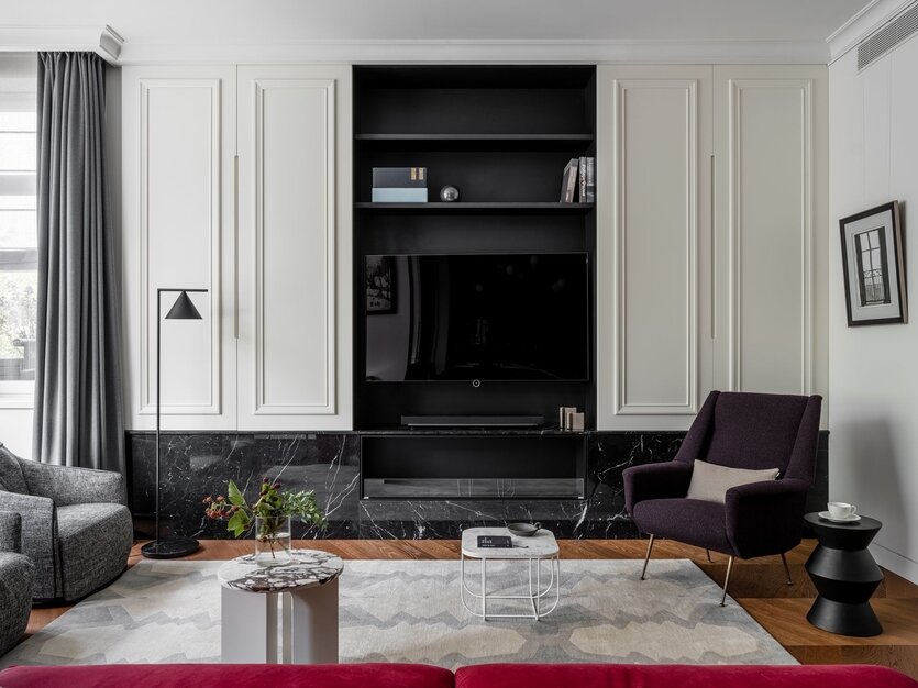 ТВ-зона спроектирована по авторскому проекту. За белыми панелями, выполненными в столярной мастерской, скрываются места хранения. Чёрная ниша удачно маскирует телевизор. Под ним расположен камин Decoflame, о котором мечтал хозяин дома.