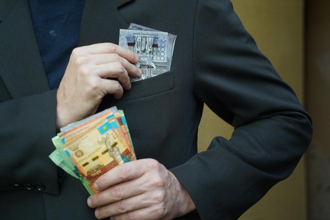    Мужчина кладет деньги в нагрудный карман:NUR.KZ/Владимир Третьяков