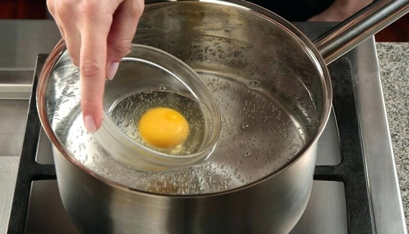 Вода в кастрюле должна быть горячей, но не сильно кипящей, лишь с небольшим количеством пузырьков. В бурлящей жидкости яйцо просто распадётся.