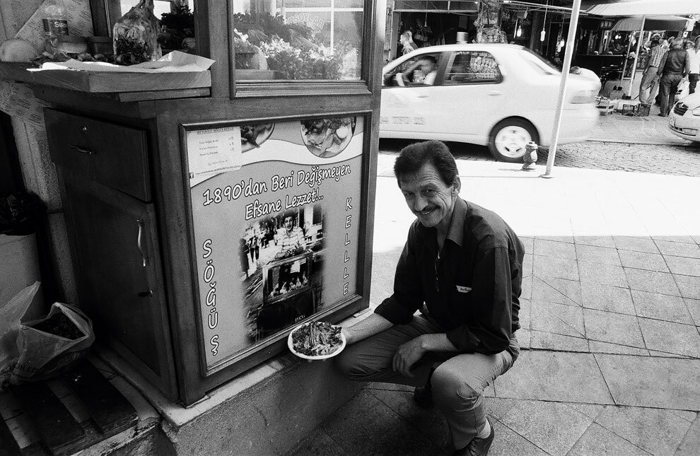 Муаммер, хозяин шкафчика с вареными бараньими головами Beyoğlu Söğüş Kelle, позирует у фотографии, где он подросток — еще с тележкой